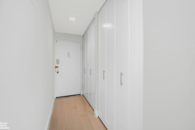 hallway with light wood-type flooring and baseboards