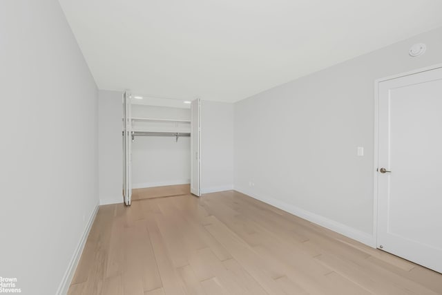 unfurnished bedroom with a closet, baseboards, and light wood-style flooring