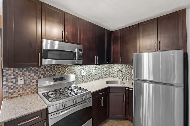 kitchen featuring sink, appliances with stainless steel finishes, dark brown cabinets, tasteful backsplash, and light stone countertops