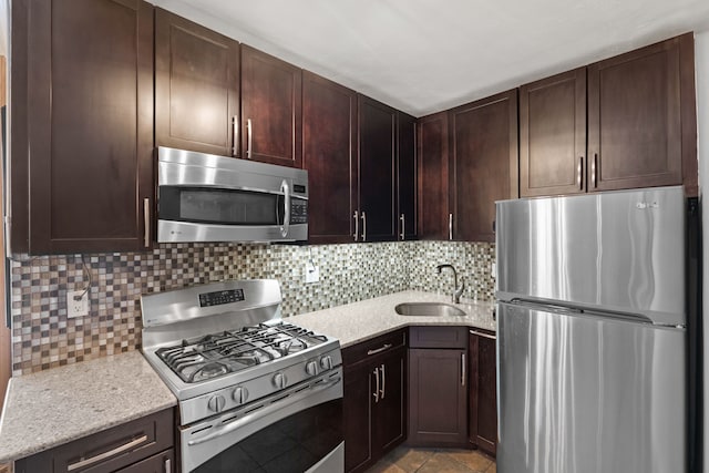 kitchen with dark brown cabinetry, appliances with stainless steel finishes, backsplash, and a sink