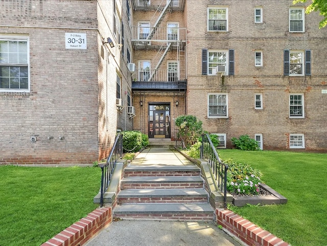 entrance to property with cooling unit and a lawn