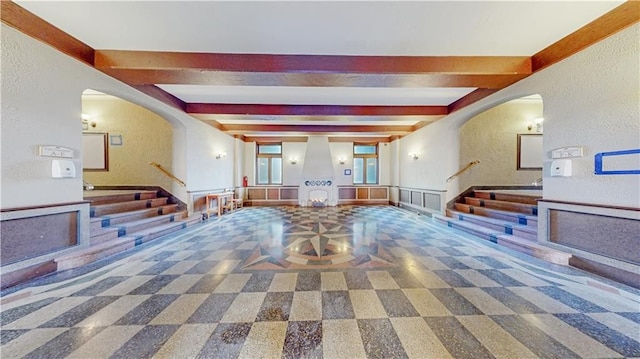 interior space featuring arched walkways, a textured wall, and stairway