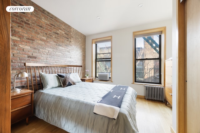 100 Suffolk St Unit 2E, New York City, NY 10002 - bedroom featuring cooling unit, wood finished floors, brick wall, and radiator