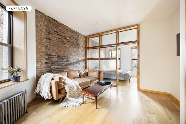 living room with radiator, light hardwood / wood-style flooring, and brick wall