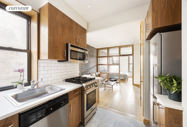 kitchen featuring appliances with stainless steel finishes, brown cabinetry, and a sink