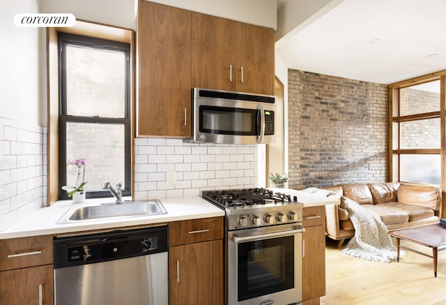 kitchen featuring light wood-type flooring, appliances with stainless steel finishes, sink, and backsplash