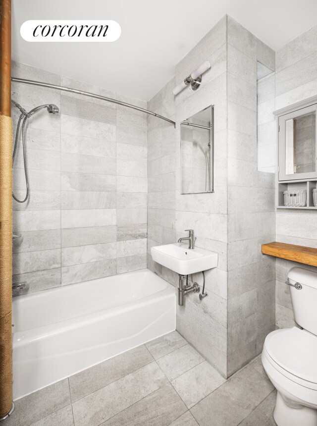 full bathroom with sink, tile walls, tiled shower / bath combo, toilet, and tile patterned floors