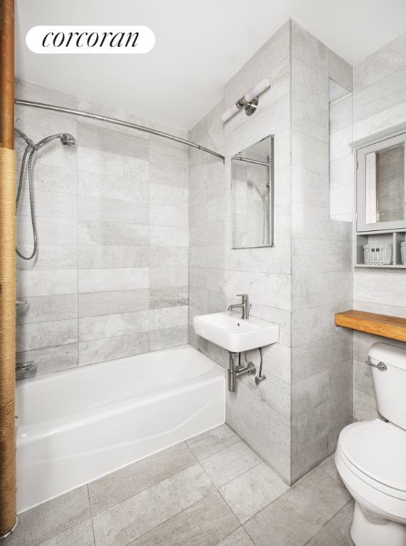 full bath featuring shower / washtub combination, tile walls, toilet, a sink, and tile patterned flooring