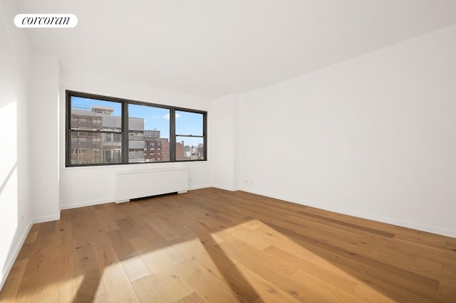 empty room featuring radiator and hardwood / wood-style floors