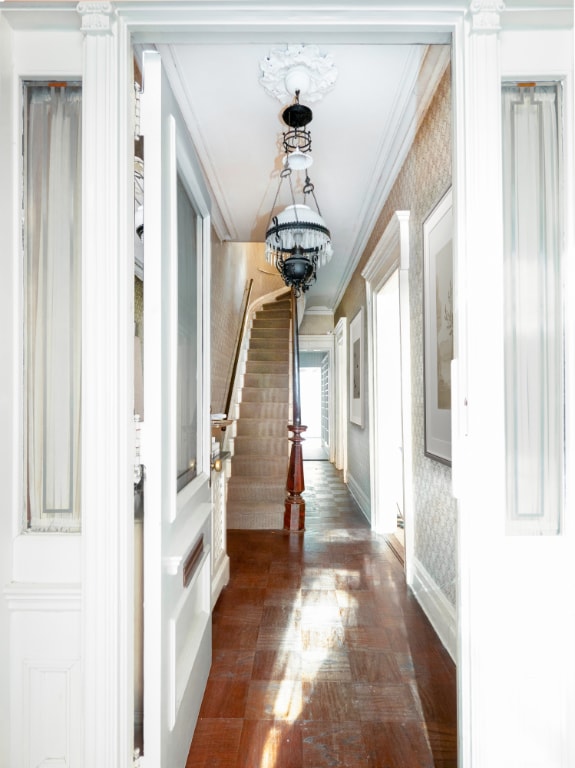 hallway with crown molding, dark hardwood / wood-style flooring, and a chandelier