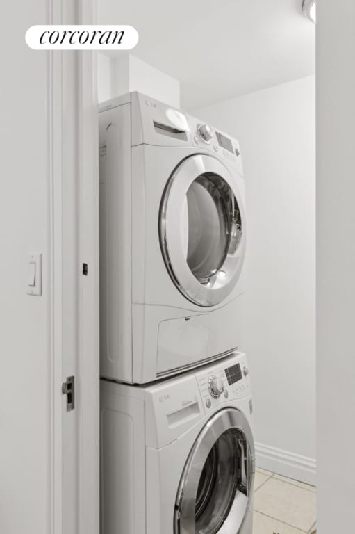 clothes washing area with stacked washer / drying machine and light tile patterned floors