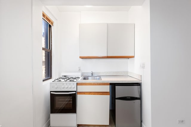 339 E 58th St Unit 7G, New York City, NY 10022 - kitchen featuring gas range gas stove, fridge, a sink, light countertops, and white cabinets