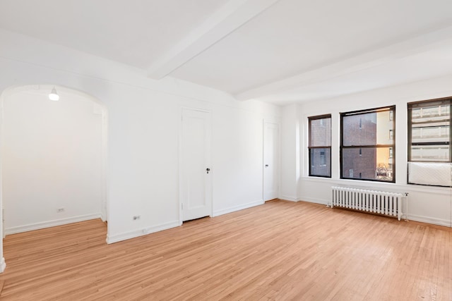 339 E 58th St Unit 7G, New York City, NY 10022 - unfurnished room featuring radiator, beamed ceiling, light wood-type flooring, healthy amount of natural light, and arched walkways