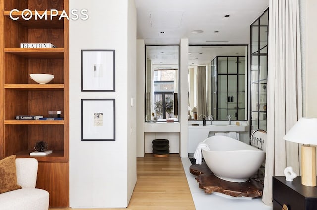 bathroom featuring hardwood / wood-style floors, a washtub, and built in shelves