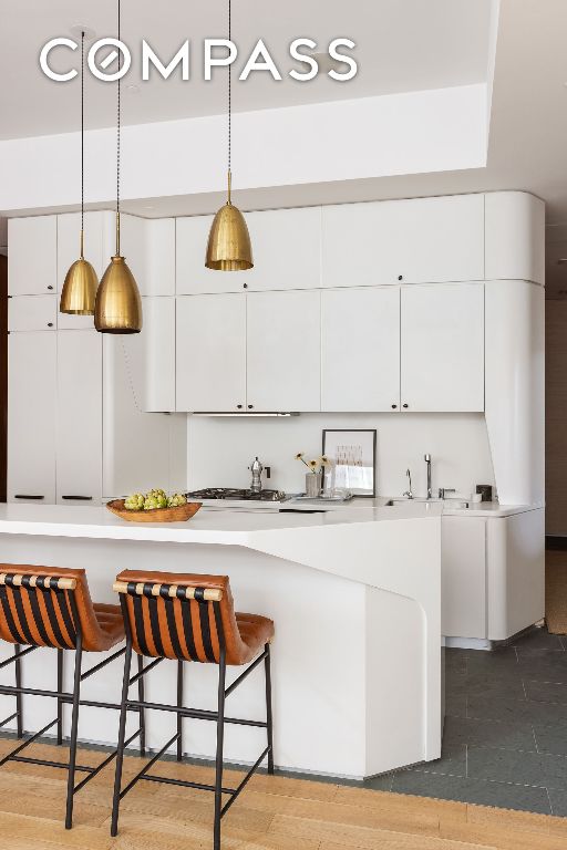 kitchen featuring white cabinetry, sink, pendant lighting, and a kitchen bar