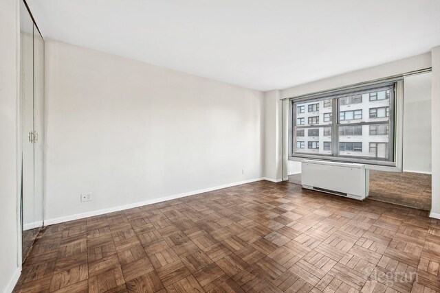 empty room featuring an inviting chandelier, crown molding, and dark parquet floors