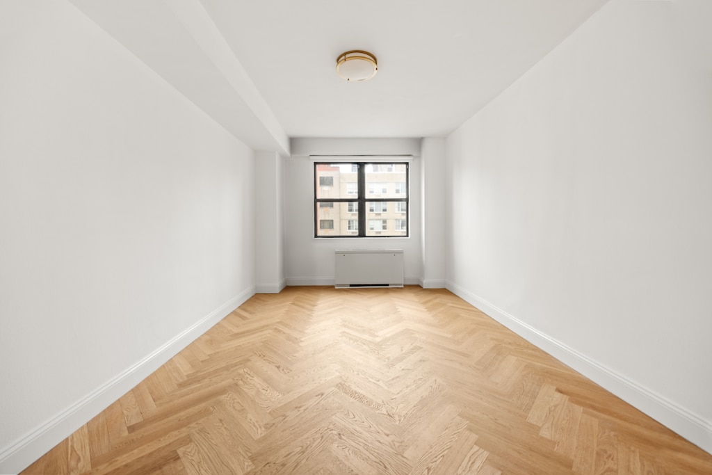 empty room featuring radiator heating unit and light parquet floors