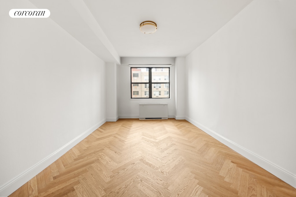 unfurnished room featuring baseboards, visible vents, and radiator heating unit