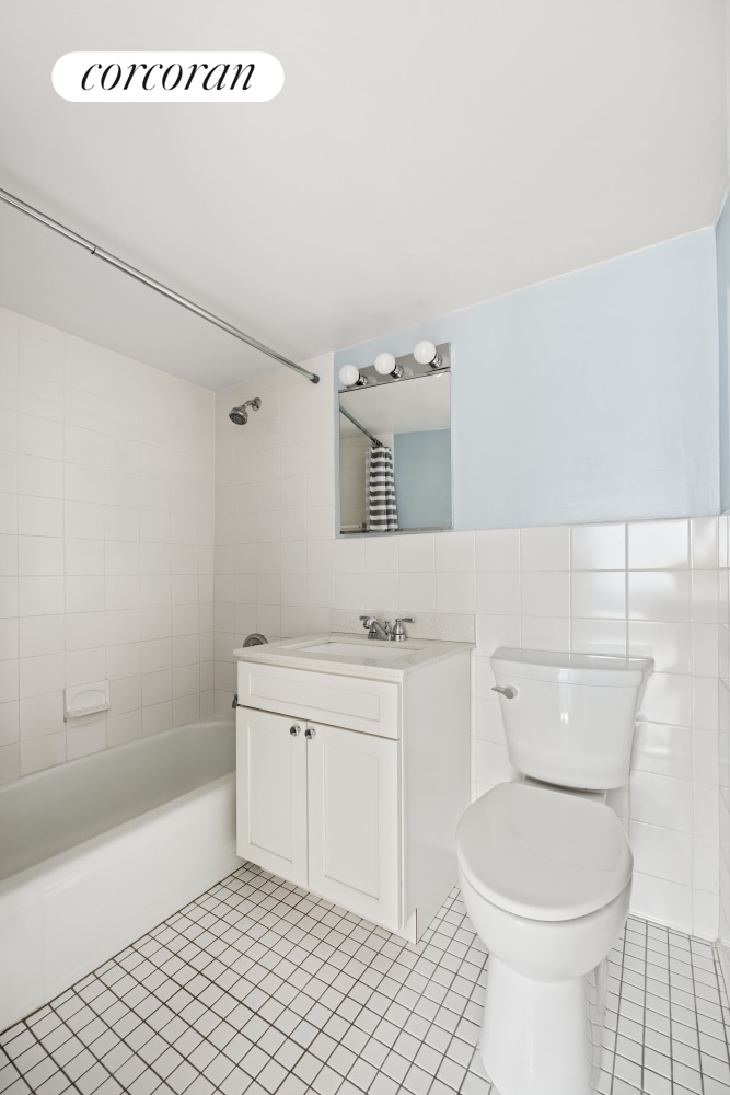 full bath featuring shower / bathtub combination, tile patterned flooring, toilet, vanity, and tile walls