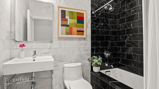 full bathroom featuring shower / bathtub combination with curtain, sink, tile walls, and toilet