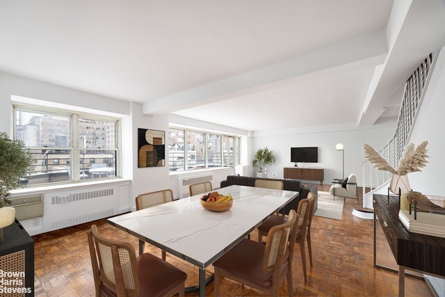 dining room featuring radiator heating unit, dark parquet floors, and beamed ceiling