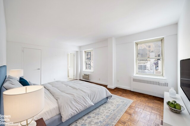 bedroom featuring parquet flooring, radiator, and an AC wall unit