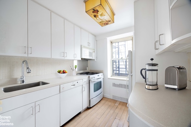 kitchen featuring radiator heating unit, tasteful backsplash, white cabinetry, sink, and white appliances