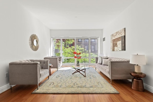 living room featuring visible vents, baseboards, and wood finished floors