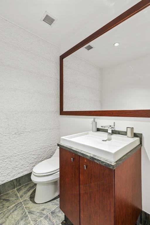 half bathroom with visible vents, toilet, and vanity