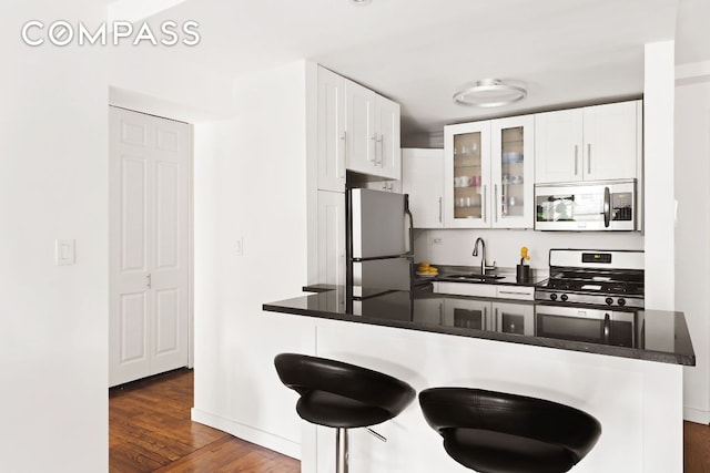 kitchen featuring appliances with stainless steel finishes, sink, white cabinets, and kitchen peninsula