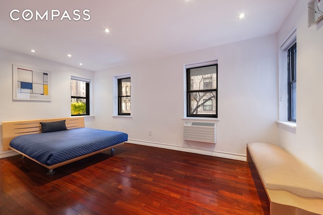 bedroom with baseboards, a wall mounted air conditioner, and hardwood / wood-style floors