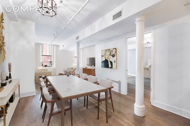 dining room featuring wood finished floors, visible vents, and ornate columns