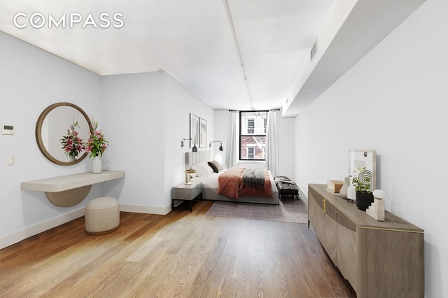 bedroom with baseboards, wood finished floors, and visible vents