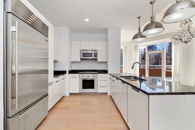 kitchen with modern cabinets, appliances with stainless steel finishes, light wood-type flooring, white cabinetry, and a sink