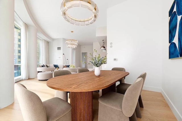 dining room featuring light wood-style flooring, baseboards, and a chandelier