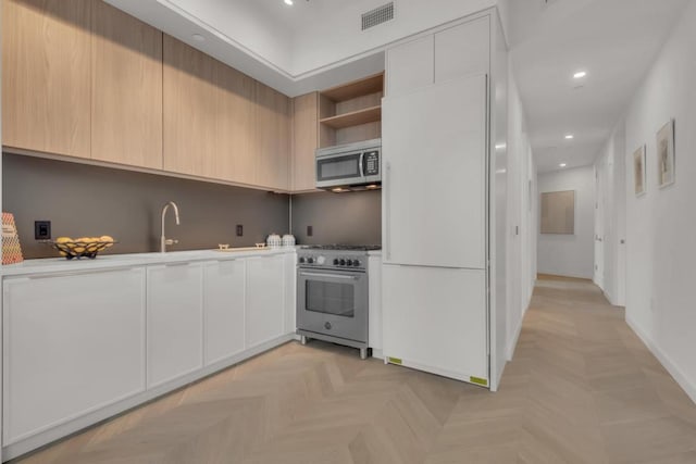 kitchen featuring light parquet flooring, appliances with stainless steel finishes, sink, and light brown cabinetry