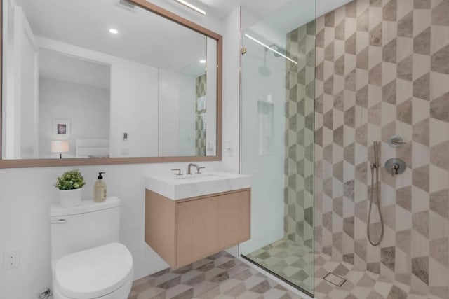 bathroom with vanity, toilet, and tiled shower