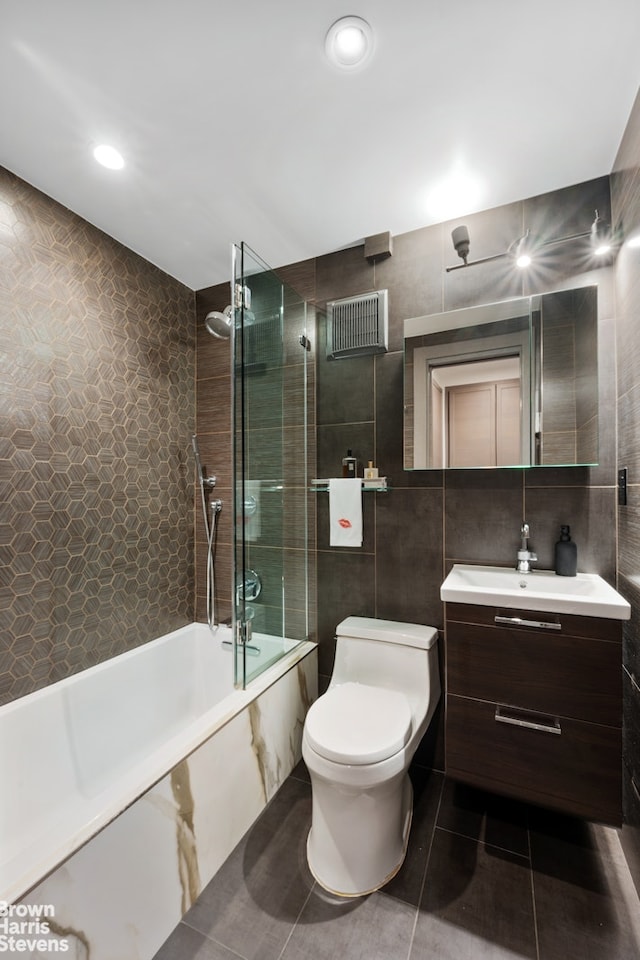 full bath with tile walls, toilet, tile patterned floors, vanity, and shower / washtub combination