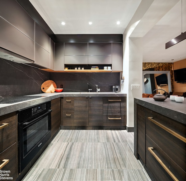 kitchen featuring black oven, modern cabinets, and stovetop