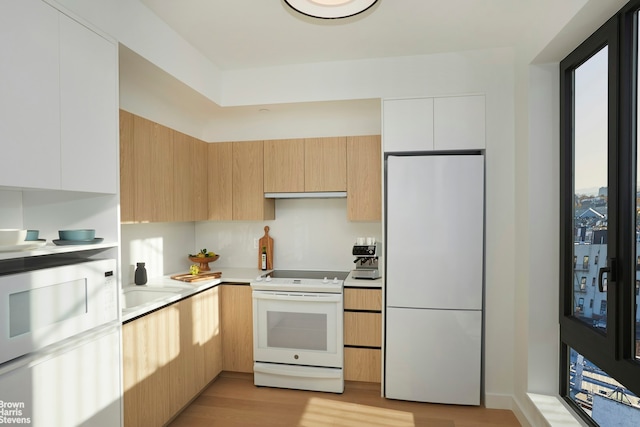 kitchen featuring under cabinet range hood, light wood-type flooring, light countertops, white appliances, and modern cabinets