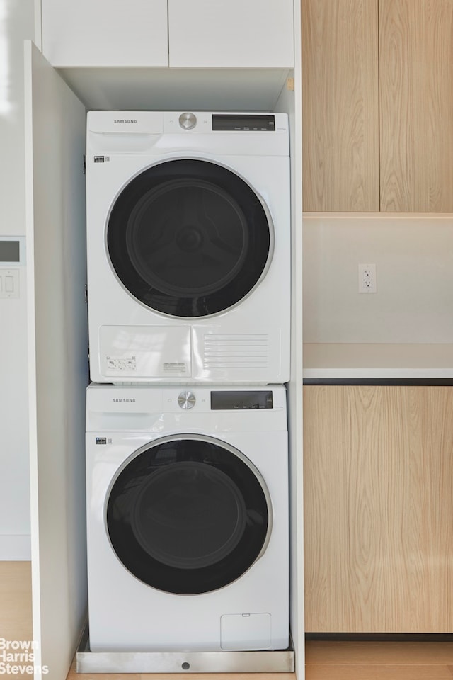 laundry room with light wood finished floors, laundry area, and stacked washer and clothes dryer