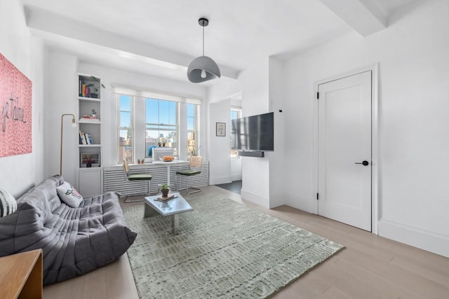 living room featuring beamed ceiling and light hardwood / wood-style floors