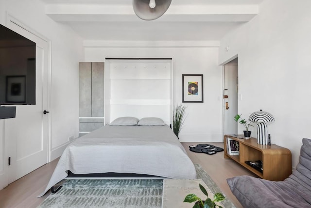 bedroom featuring beamed ceiling and wood-type flooring