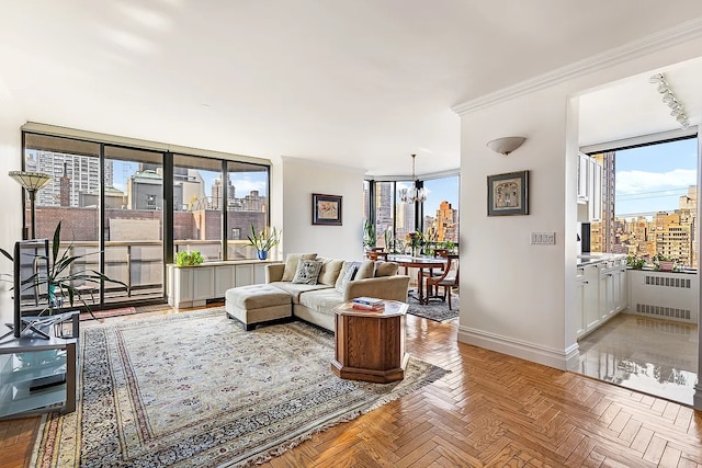 living room with radiator heating unit, crown molding, a city view, an inviting chandelier, and baseboards