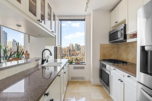 kitchen featuring white cabinets, glass insert cabinets, a view of city, stainless steel appliances, and a sink