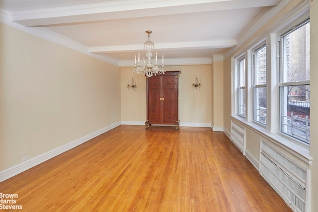 spare room with beamed ceiling, ornamental molding, a chandelier, and light hardwood / wood-style floors