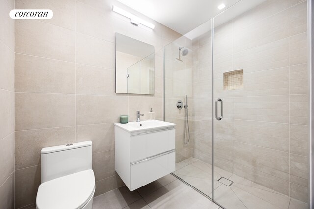 bathroom featuring toilet, an enclosed shower, tile walls, vanity, and tile patterned flooring