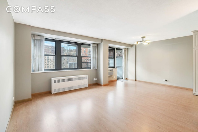 spare room featuring radiator, baseboards, and wood finished floors