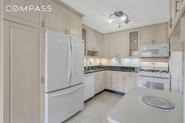 kitchen with tasteful backsplash, cream cabinets, sink, and white appliances