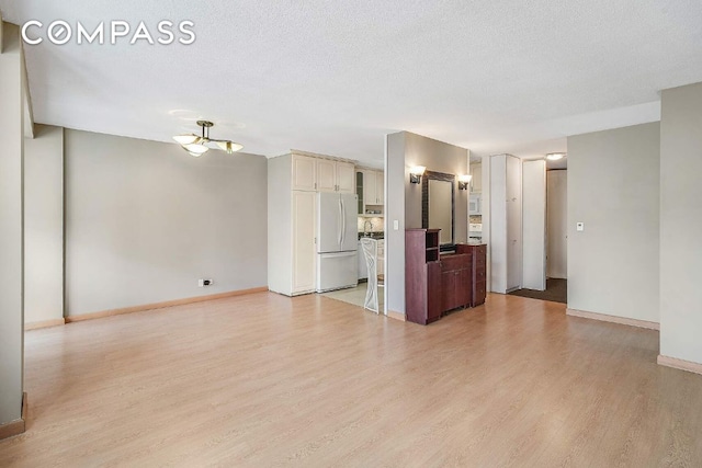 unfurnished living room featuring a textured ceiling and light hardwood / wood-style floors